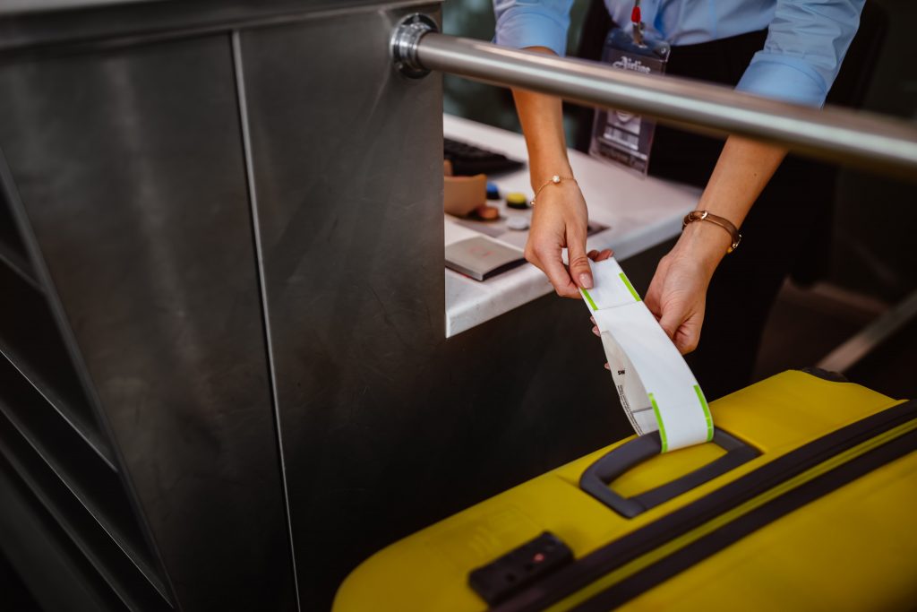 Airport check-in officer tags a large suitcase for travellers longer stay