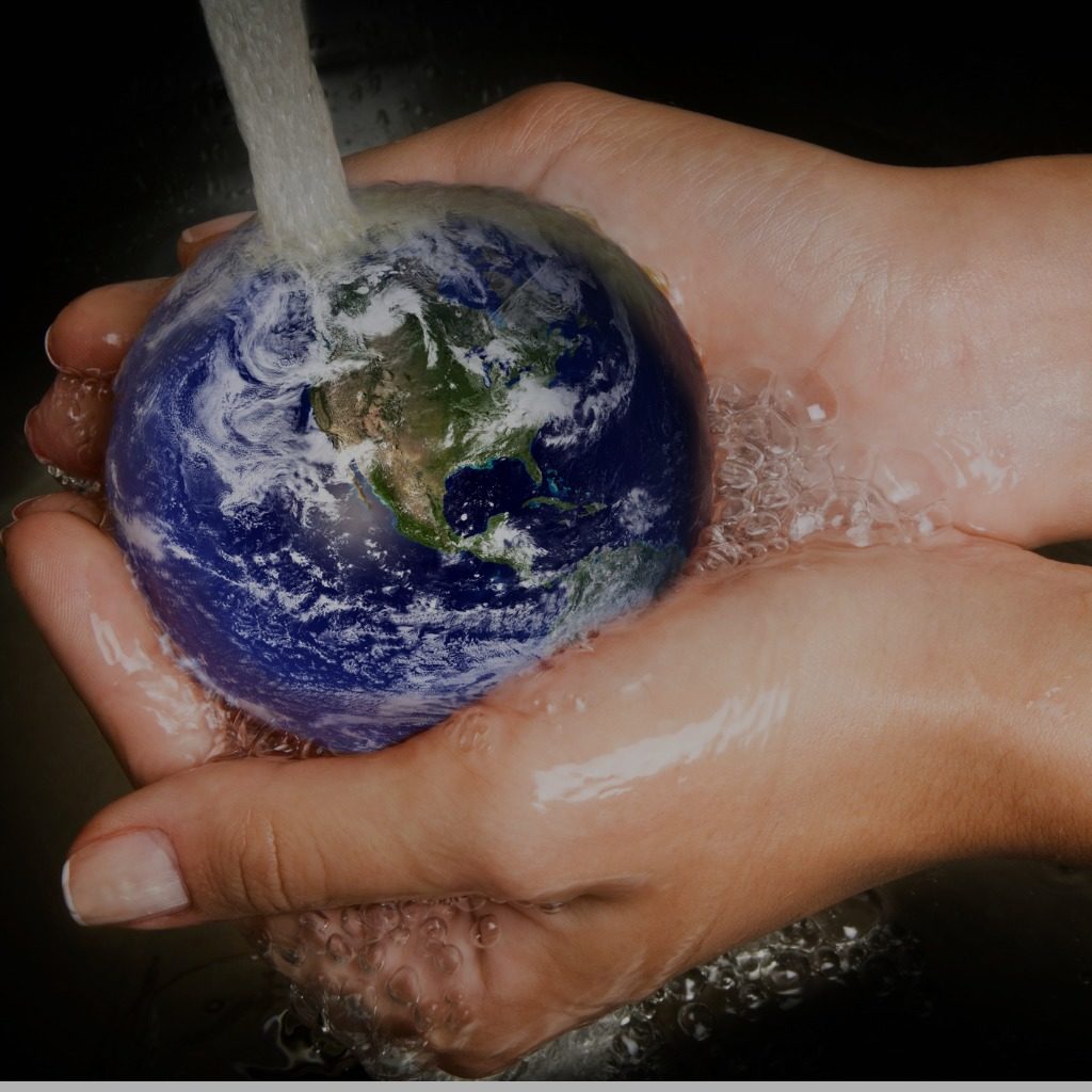 Cupped hands hold a small model of the world under a running tap